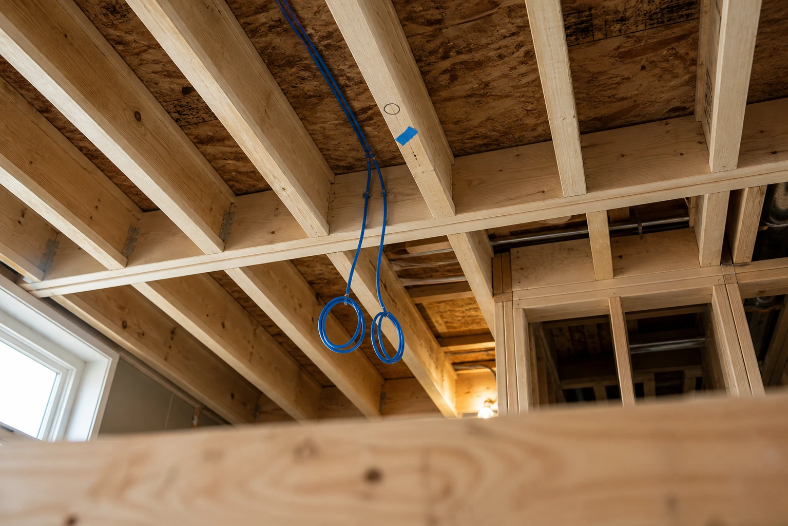 Two Cat6 cables dropped from a ceiling joist to a marked Wi-Fi access point position, properly stapled and ready for drywall - redundant pair shown