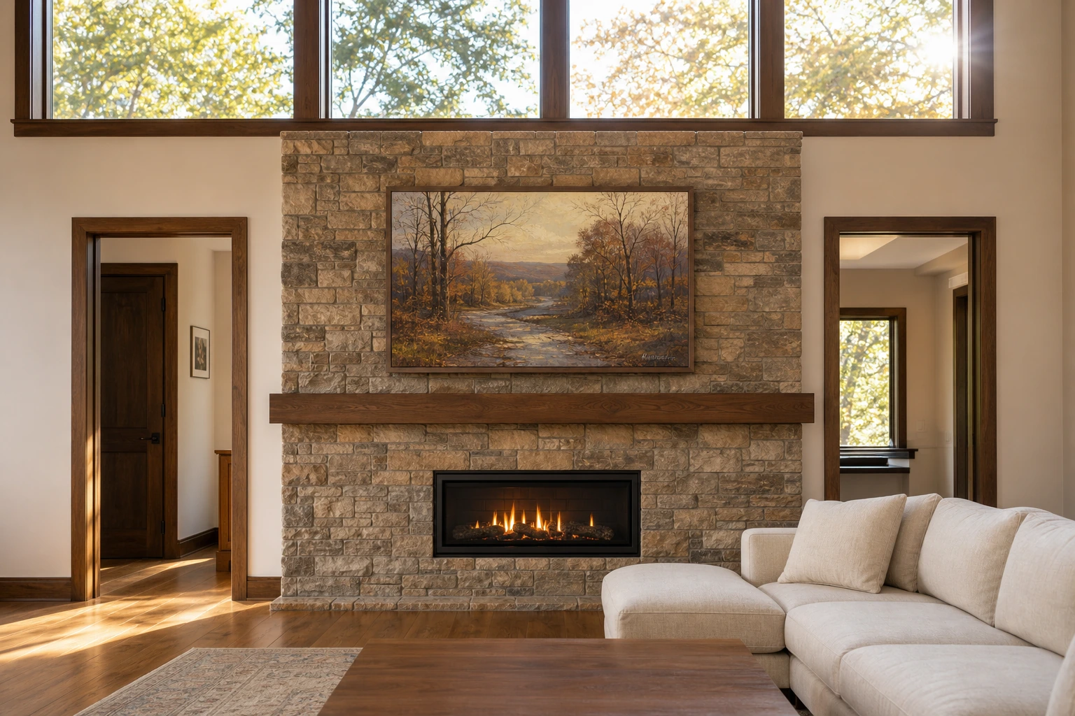 Newmarket Stonehaven-Wyndham great room with the Samsung Frame TV running Art Mode against late-afternoon south-facing daylight from the transom band of windows above the fireplace surround, screen reading as a framed painting against the stone-clad wall