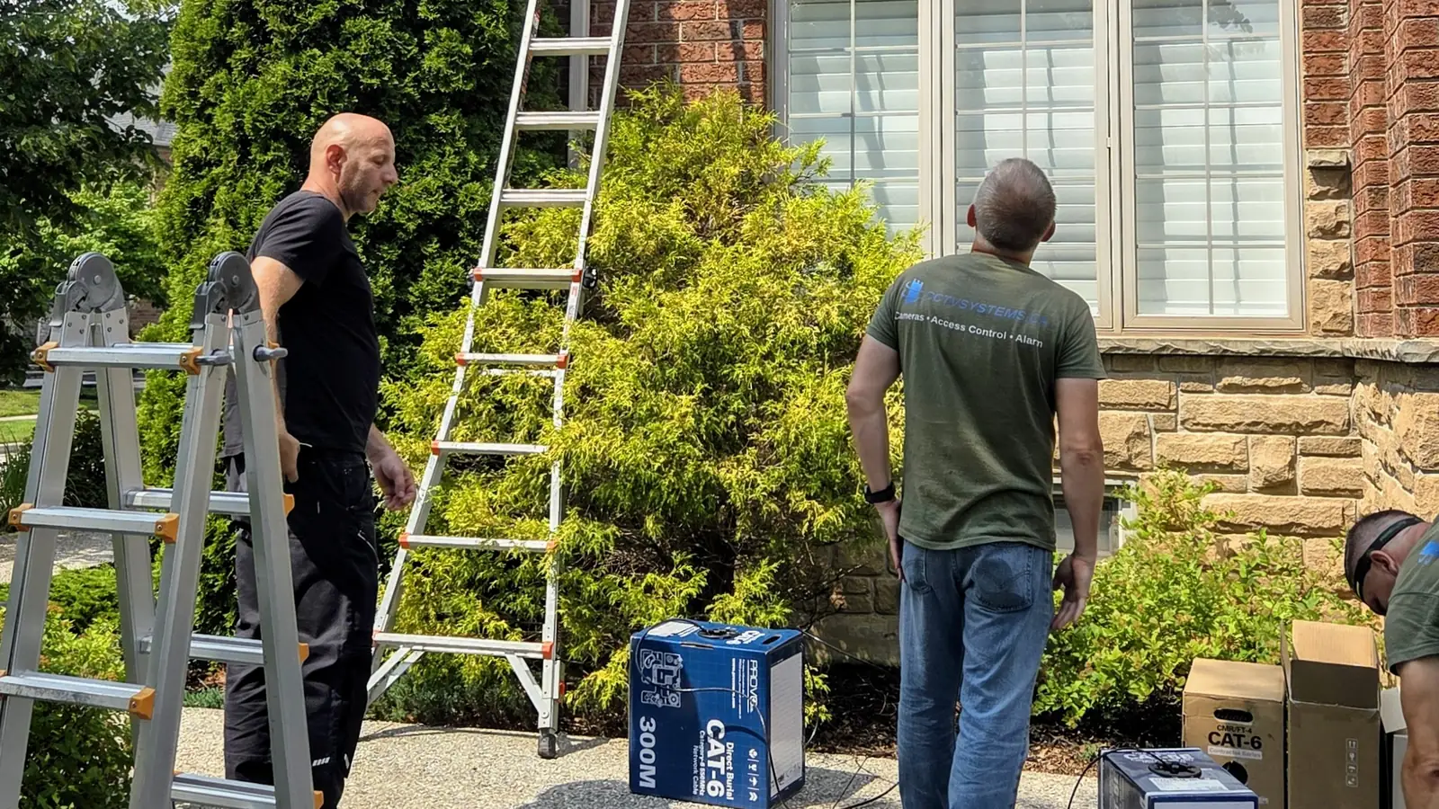 SetupTeam technicians staging ladders and a spool of outdoor-rated direct-burial Cat6 cable outside a finished brick home in Oakville, Ontario