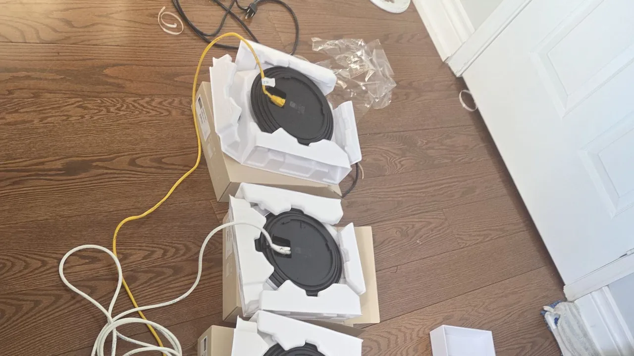 UniFi access points unboxed and cabled on the floor, staged for adoption before mounting