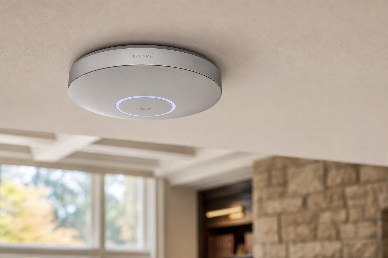 Close-up of a UniFi U7 Pro Max Wi-Fi 7 access point ceiling-mounted in a Hills of St. Andrew Aurora two-storey great room, showing the brushed-aluminum housing and PoE backhaul