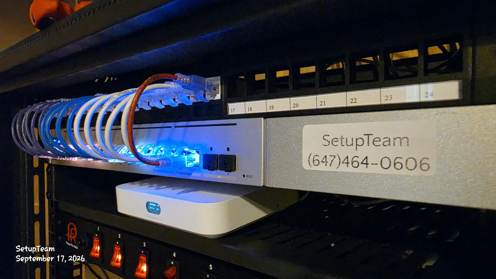 UniFi Cloud Gateway and PoE switch in a network rack below a numbered, labelled patch panel