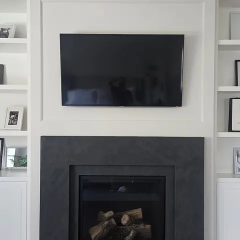 Professional TV wall mounting installation above a modern fireplace feature wall in Richmond Hill.