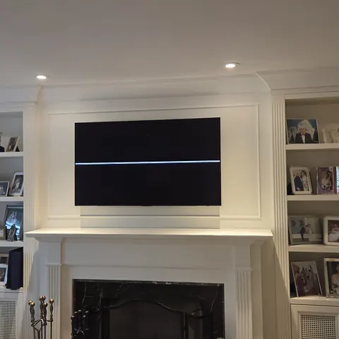 Professional TV wall mounting installation above a traditional fireplace with custom built-in shelving in North York.