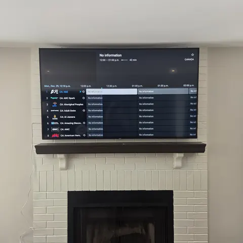 TV wall mounting installation above a painted white brick fireplace with concealed wiring and centered placement in Newmarket.