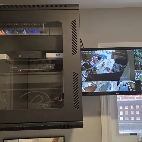 Wall-mounted network rack with UniFi networking system, security camera recorder, and live monitoring display installation in Markham.