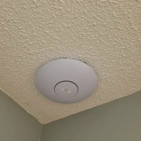 UniFi ceiling-mounted Wi-Fi access point flush-fitted into a stipple-textured residential ceiling, labelled AP2