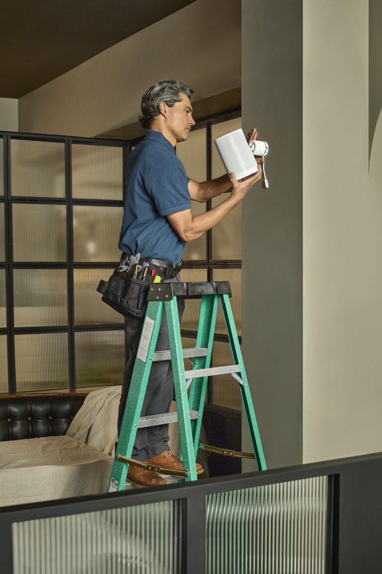 Installer mounting a speaker high on a wall