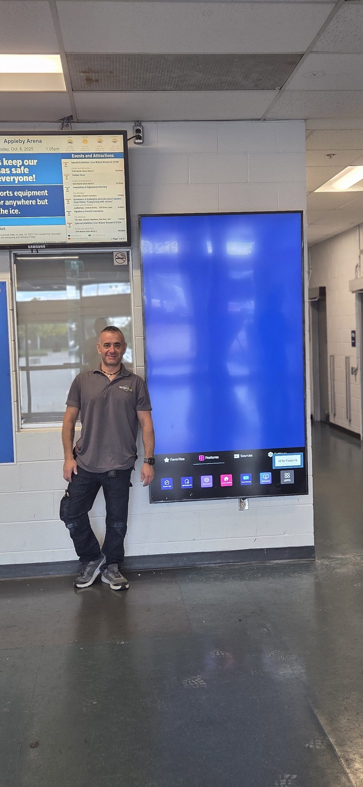 SetupTeam installer beside an 85-inch TV wall mounted in a commercial space