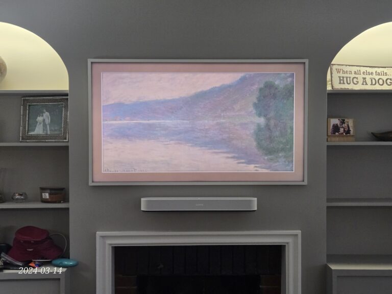 Samsung Frame TV wall-mounted above a fireplace with a Sonos Beam soundbar installed.