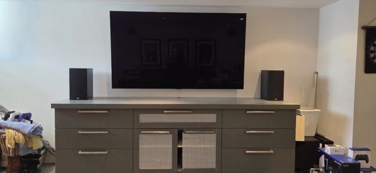 LG OLED TV installed above a media cabinet with home theatre speakers on both sides