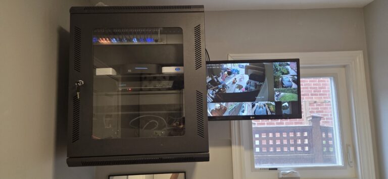 Wall-mounted equipment rack with a UniFi network switch, security camera NVR, and audio distribution components.