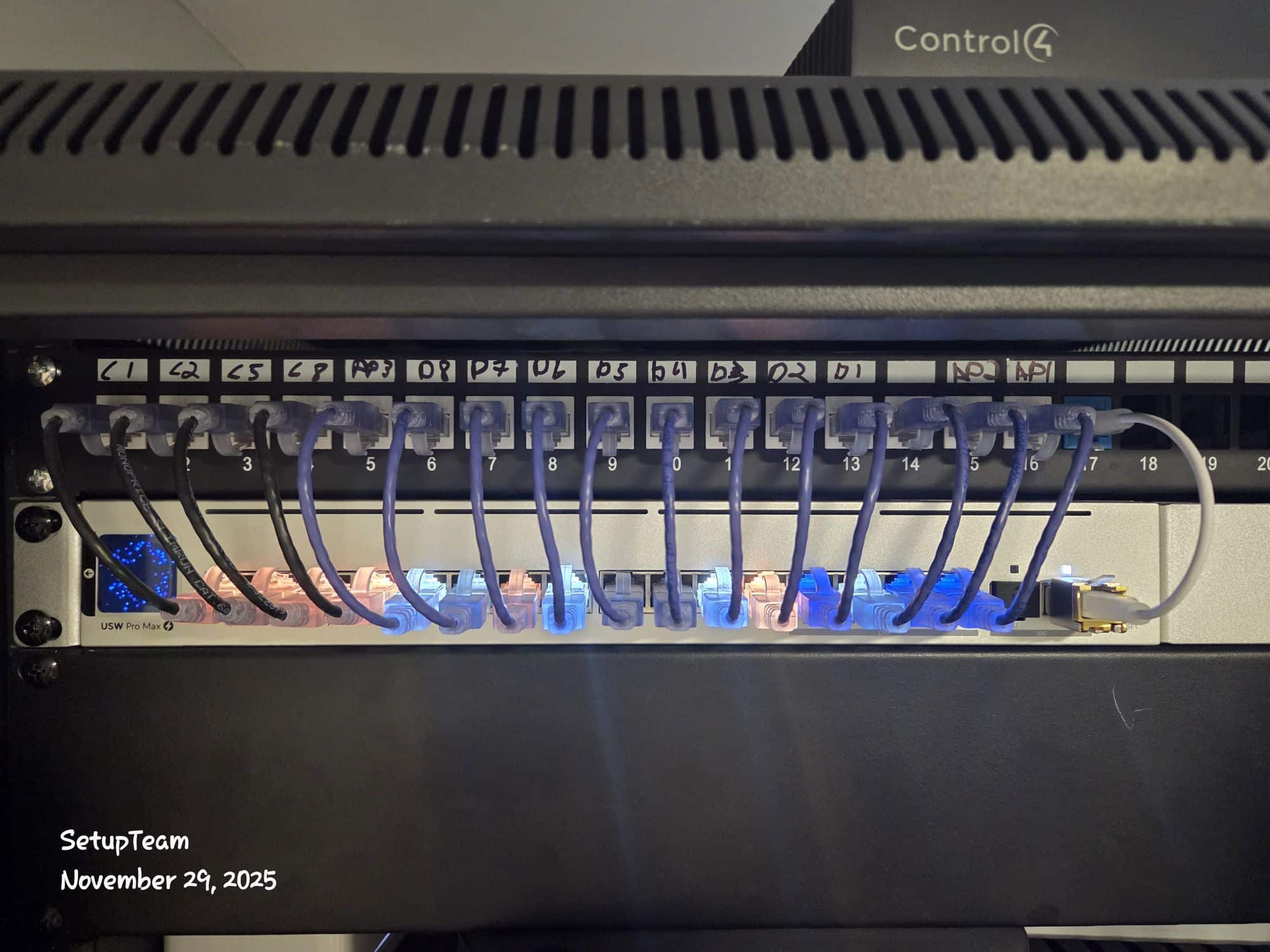 Professional network rack showing a UniFi switch and Control4 controller with neatly terminated Ethernet cables for a whole-home Wi-Fi and smart home system.