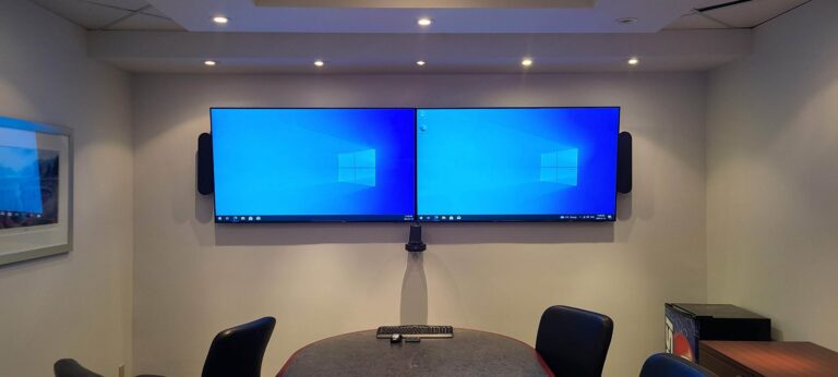 Conference room with Logitech Rally Plus video conferencing system and two 65-inch wall-mounted displays