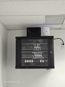 Wall-mounted network rack with organized patch panel and equipment supporting office Wi-Fi and