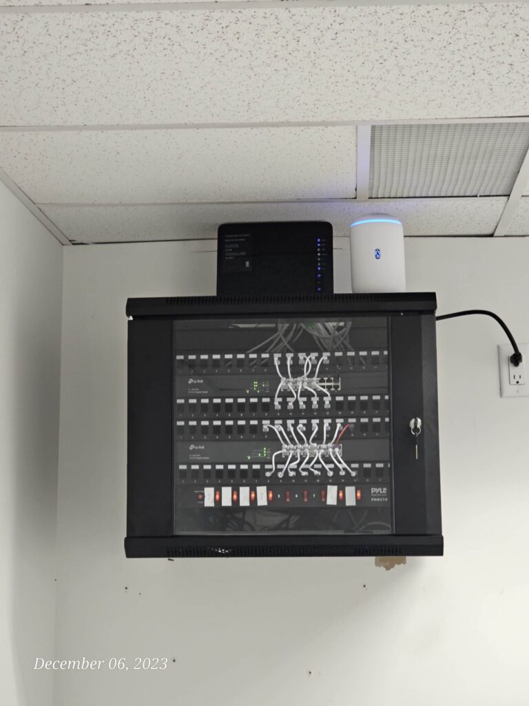 Wall-mounted network rack with organized patch panel and equipment supporting office Wi-Fi and