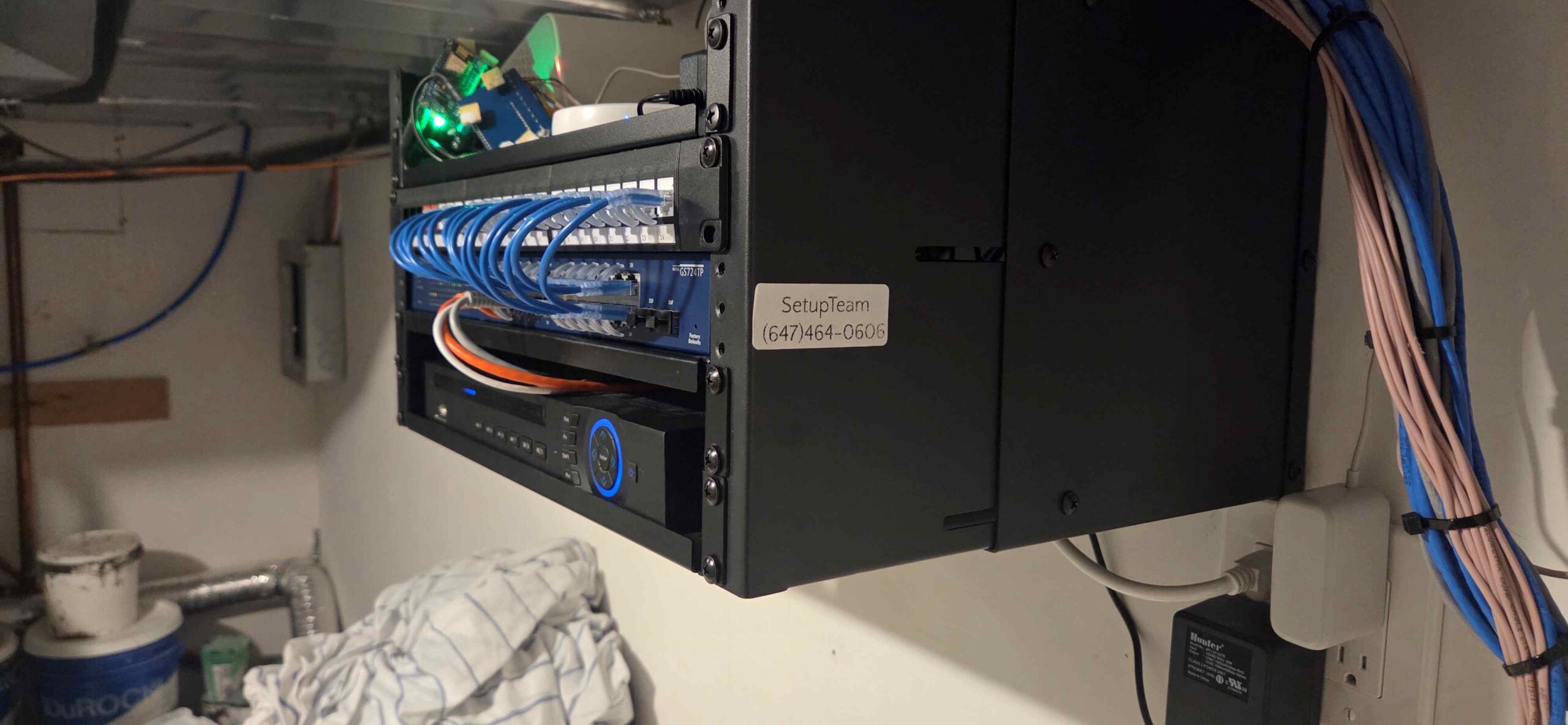 Wall-mounted network rack with structured cabling and UniFi equipment installed in a utility area