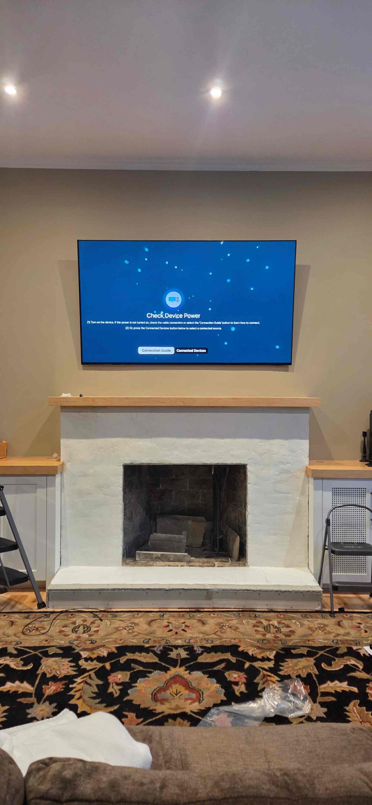 TV mounted above a fireplace on a stone feature wall in a living room