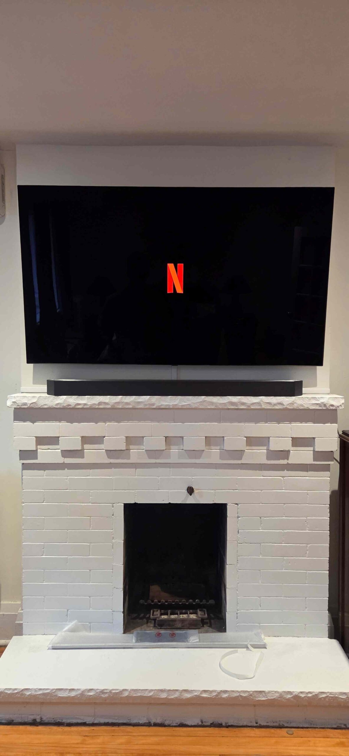 TV mounted above a white fireplace with a soundbar in a finished living room