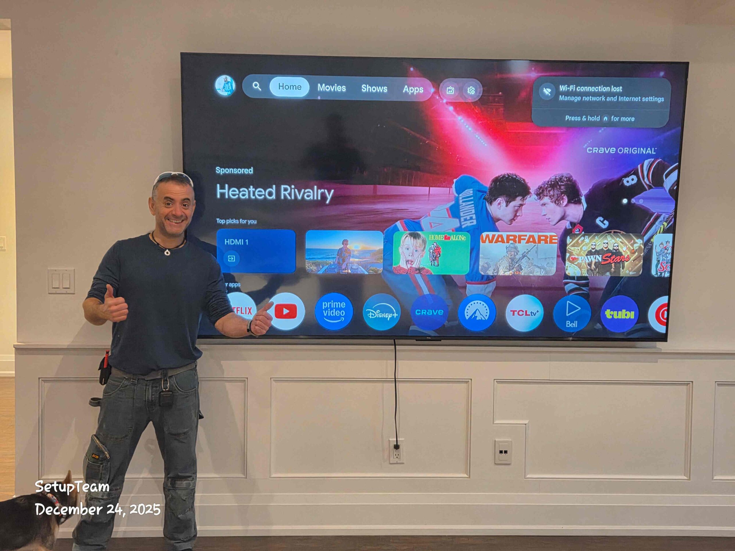 Large flat-screen TV wall mounted in a living room with installer standing beside it after installation
