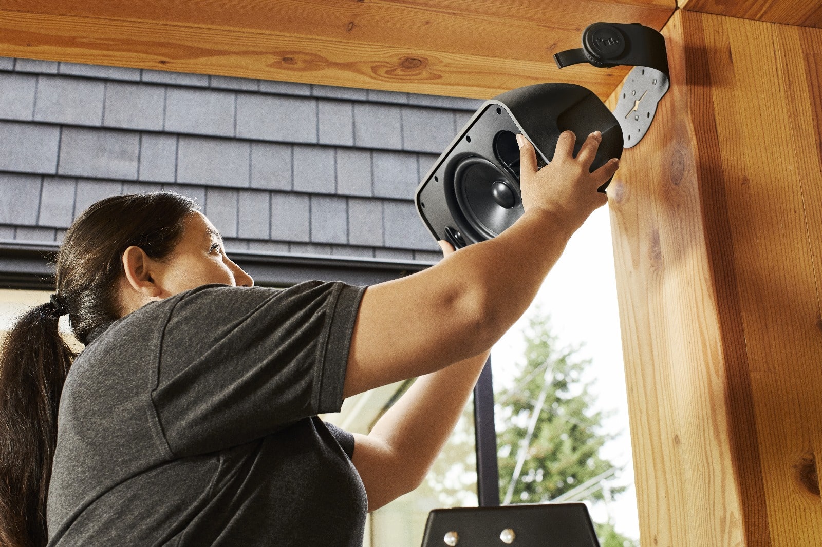 Person installing outdoor speaker.